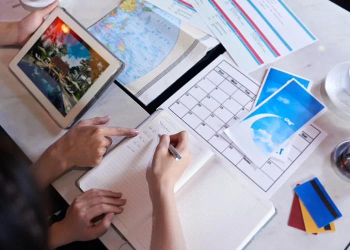 Close-up shot of unrecognizable couple taking necessary notes and planning vacation trip to Europe while sitting at table